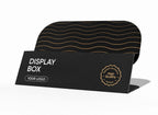 A black display box mockup with a folded front panel reading 'DISPLAY BOX' and 'YOUR LOGO,' plus a circular badge that says 'High Quality Mockup.' Behind it is a curved black panel with thin gold wavy lines.