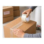 Person taping a cardboard box with a roll of tape, with another box labeled 'Fragile' in the background.