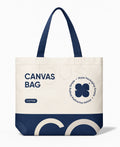 A canvas tote bag with dark navy blue handles and a navy blue bottom panel, featuring printed text and a four-leaf clover graphic on an off-white body, shown on a clean white background.