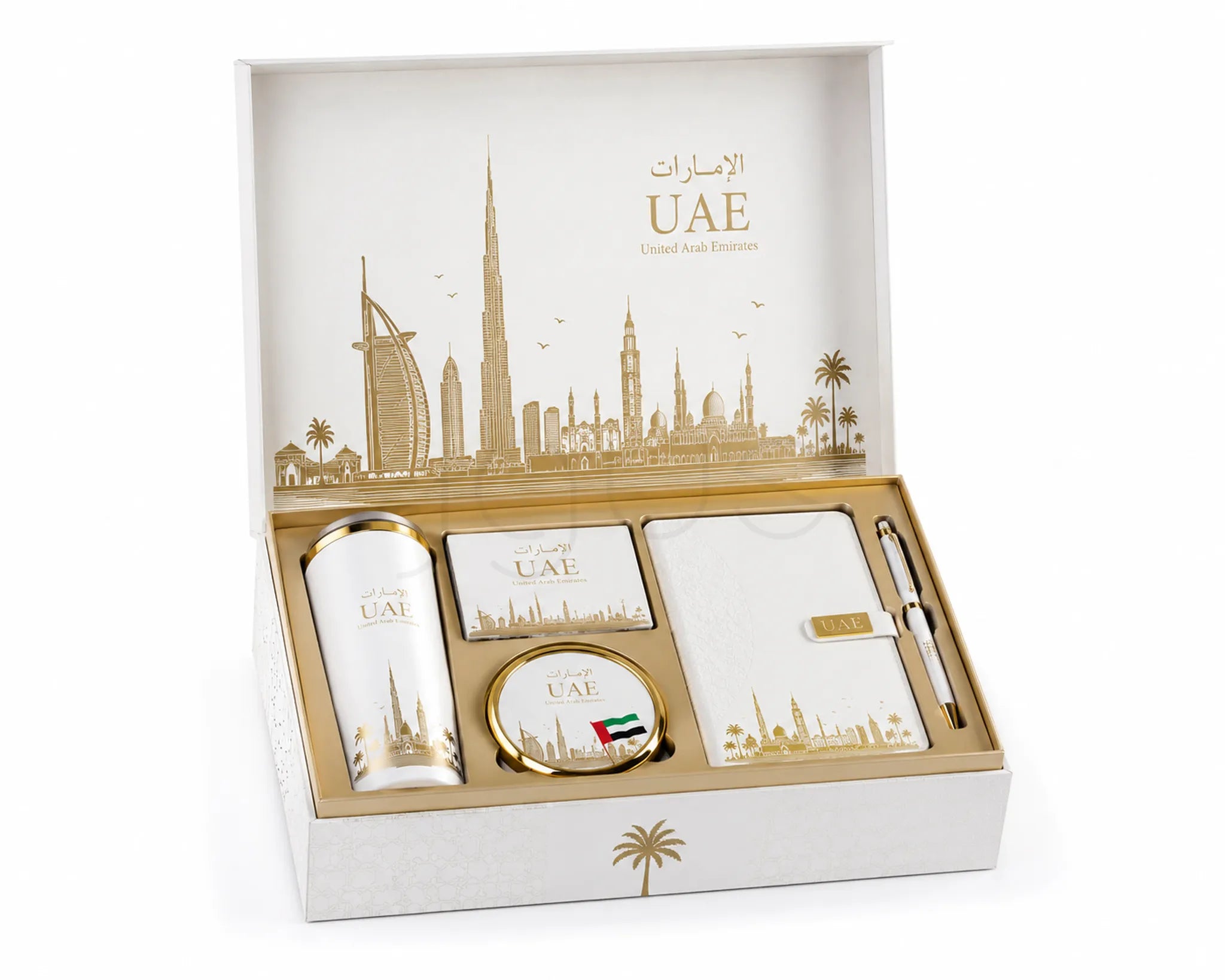 A luxury gift set in an open white box with gold UAE skyline artwork on the inside lid. The set includes a cylindrical tumbler, two small square cards, a round tin, a notebook, a pen, and a small pouch, all decorated with gold and white UAE-themed graphics.